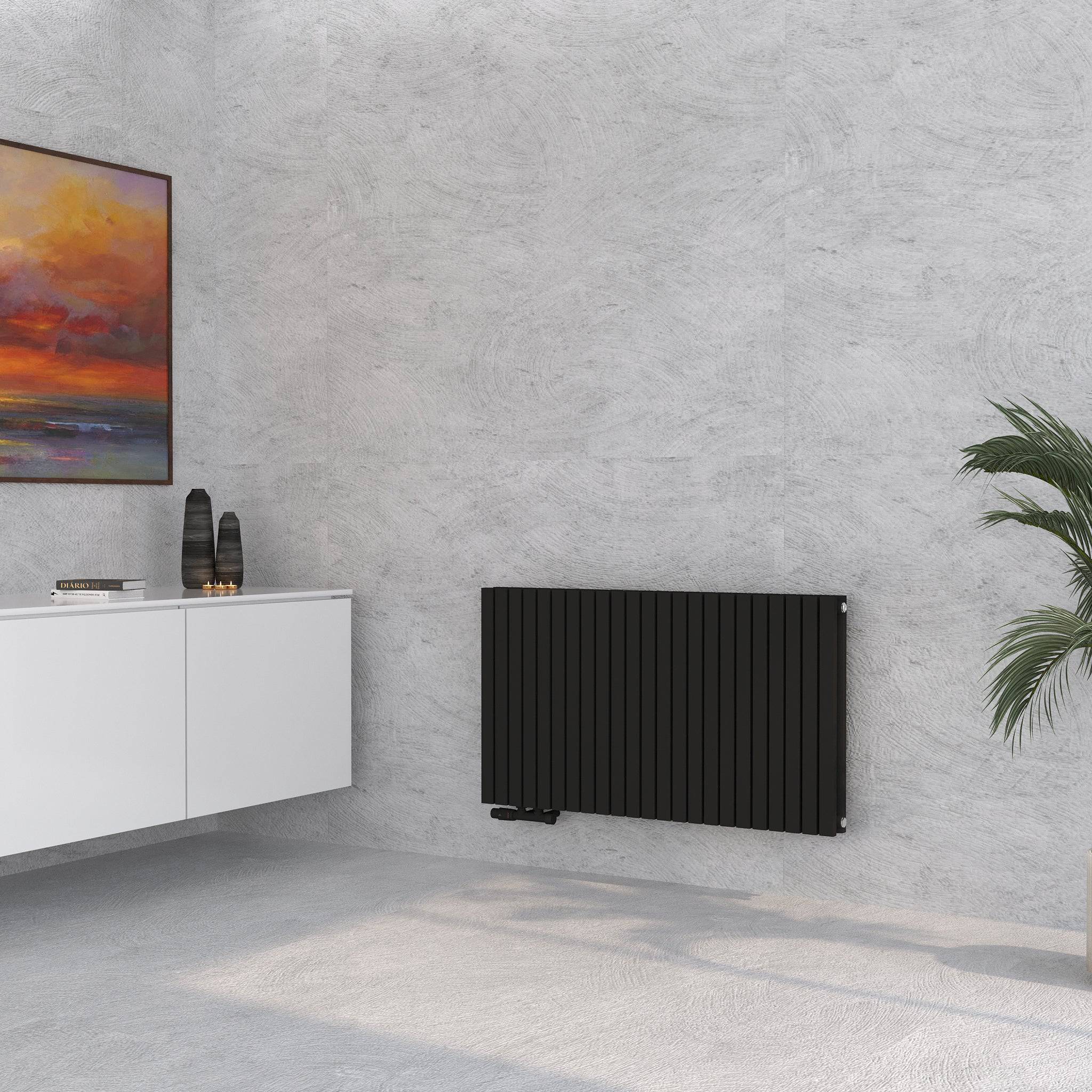 Demeter H Paneelheizkörper im Wohnraum zwischen Wandbild und Zimmerpflanze platziert